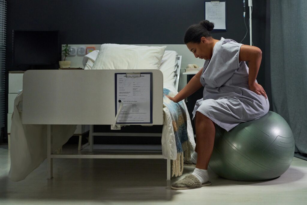 Pregnant Woman Exercising during Labor in Hospital Room