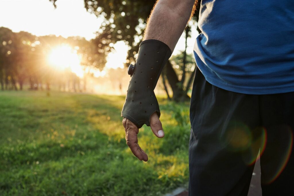 Senior sportsman wearing a hand bandage brace while exercising at a park